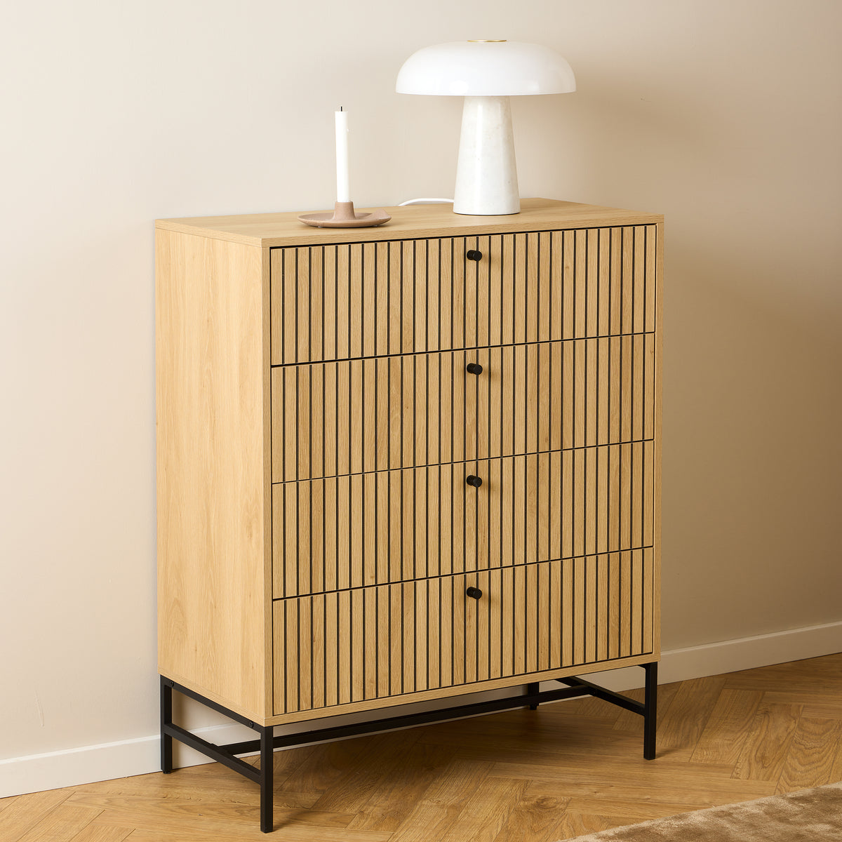 Bambouz-commode 81x100 tegen een beige muur met een witte lamp en een kaars op een parketvloer met visgraatpatroon – commode voor de slaapkamer