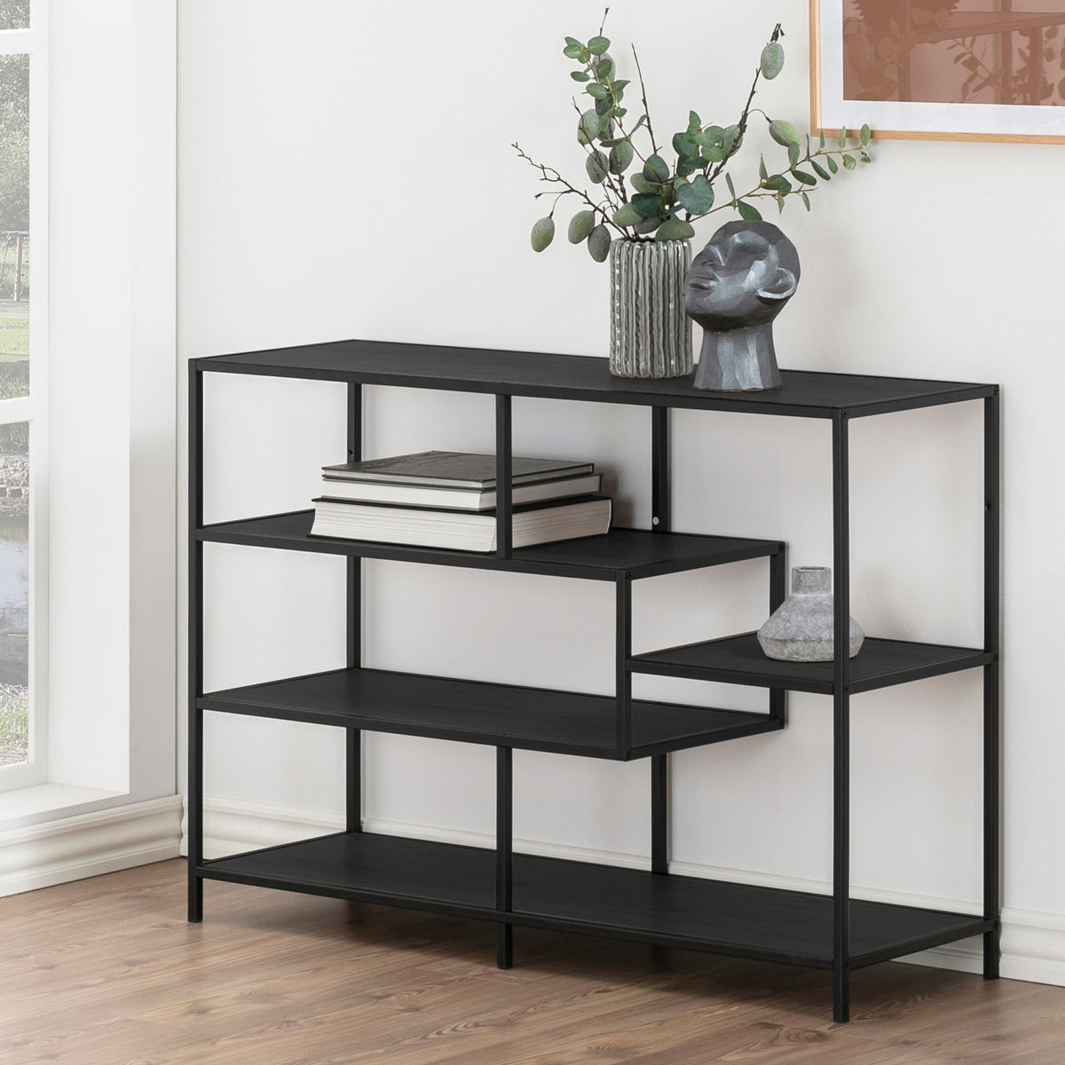 Skeleto-boekenkast 114x78, zwarte melamine, bij het raam met takjes in een vaas, een beeldje en boeken – zwarte boekenkast voor de woonkamer