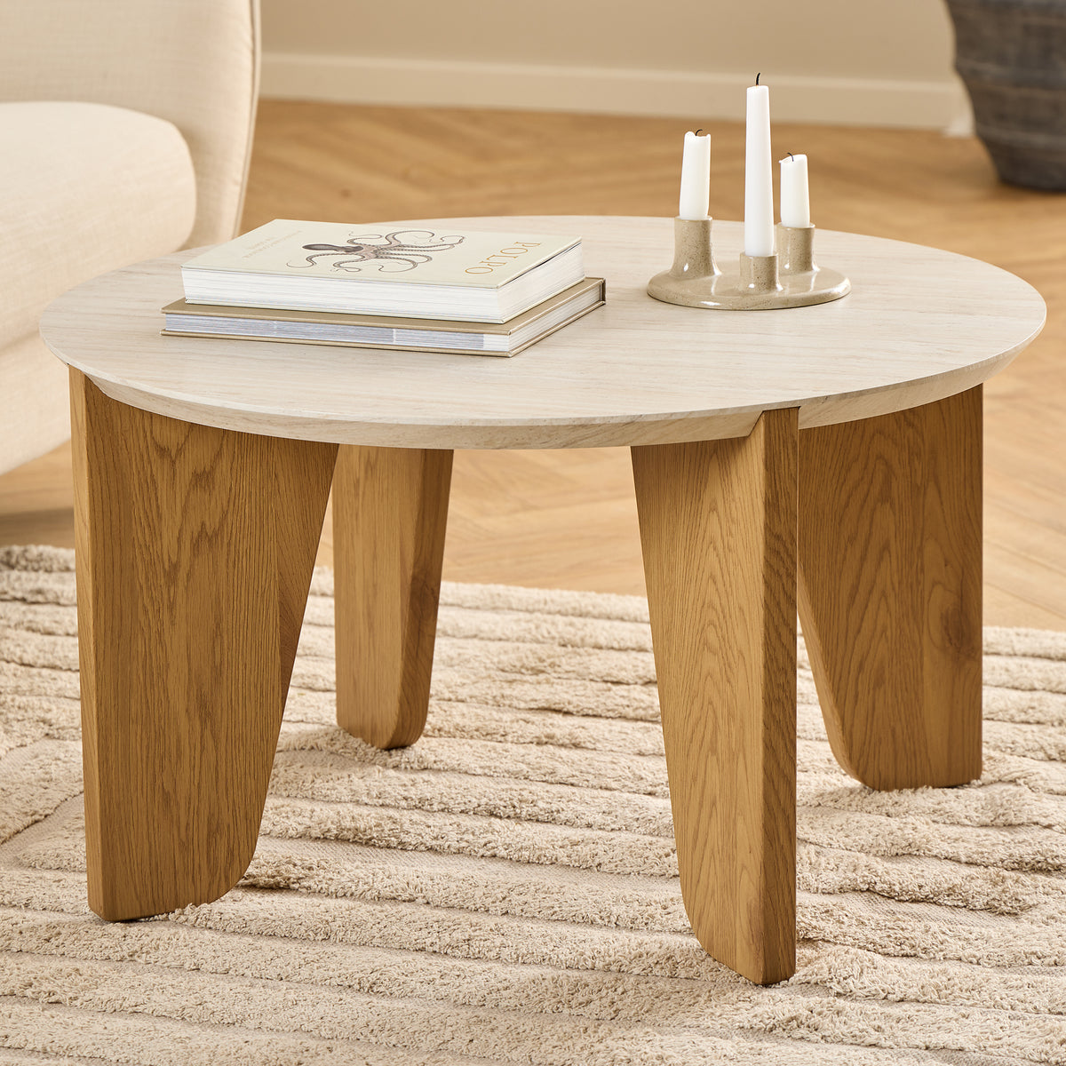 Tendra-salontafeltje Ø80x45 op een beige tapijt naast een lichte fauteuil, met boeken en een kandelaar – een salontafeltje voor de woonkamer