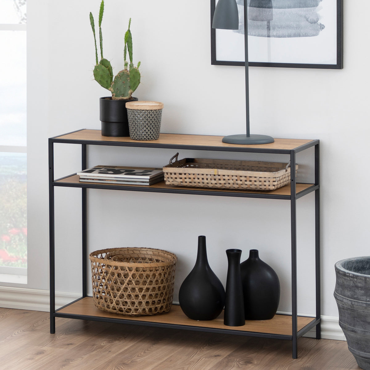 Skeleto-console 100x79 in de afwerking ‘Wild Eiken’ tegen de muur, met een cactus, een lamp, manden en zwarte vazen op de onderste plank