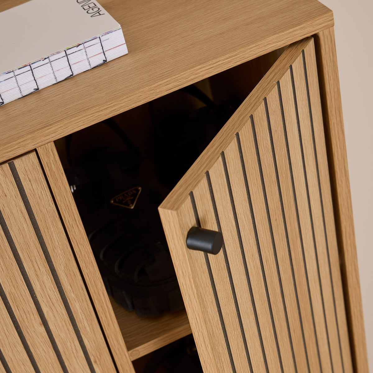 Schoenkast Bambouz 99x141 – detail van de halfopen deur met zwarte knop en schoenen op de plank