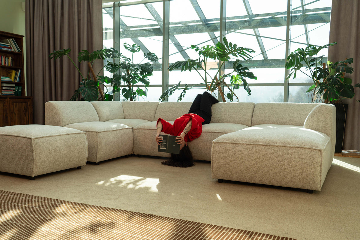 Woman relaxing on a Brick modular sofa in a bright interior full of plants.