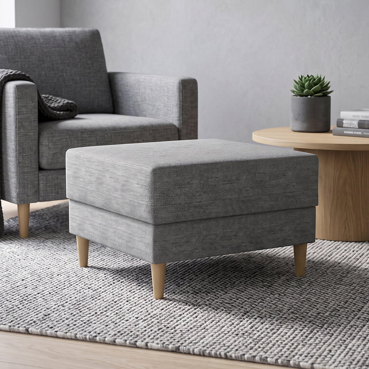 Harmi-poef 66x66 in de woonkamer voor een grijze fauteuil, naast een ronde tafel met een vetplant – poef voor de woonkamer