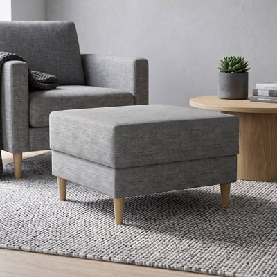 Harmi-poef 66x66 in de woonkamer voor een grijze fauteuil, naast een ronde tafel met een vetplant – poef voor de woonkamer