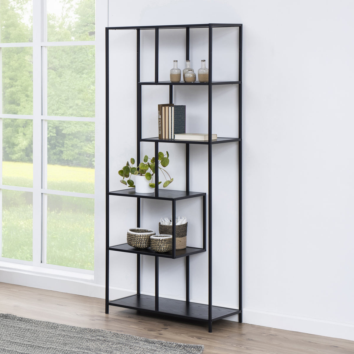 Skeleto-boekenkast 77x185, zwarte melamine, bij een groot raam met een plant, manden en boeken – zwarte boekenkast voor de woonkamer
