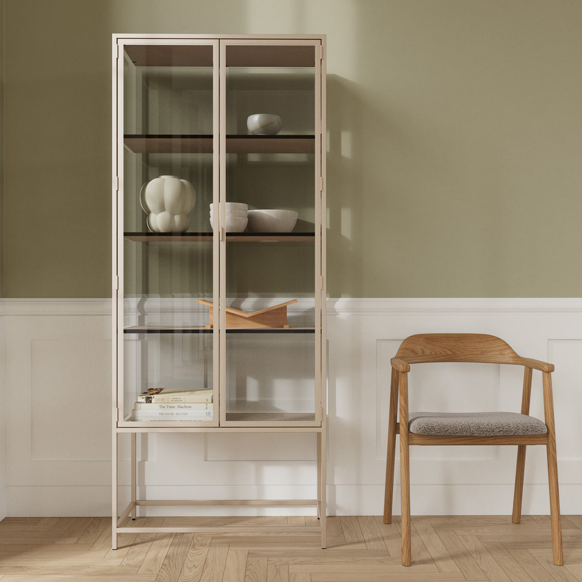 Vitrine Skeleto 77x186 grijze melamine tegen een olijfgroene muur naast een houten stoel – een vitrine voor keramiek en boeken
